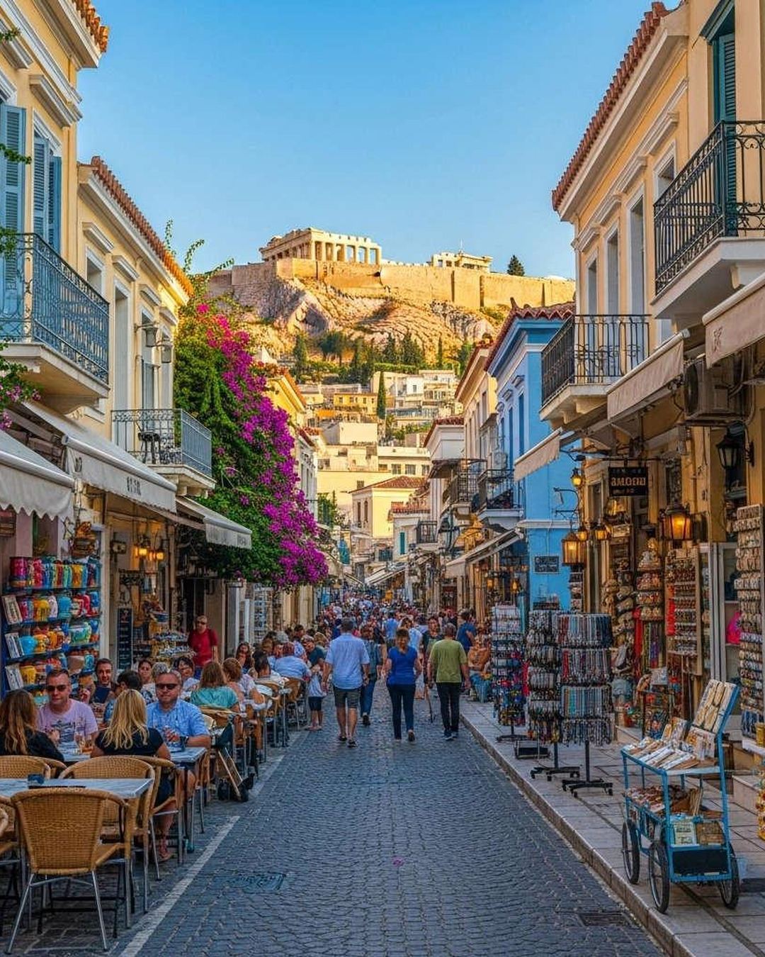 A lively Plaka street lined with cafés, with the Acropolis behind