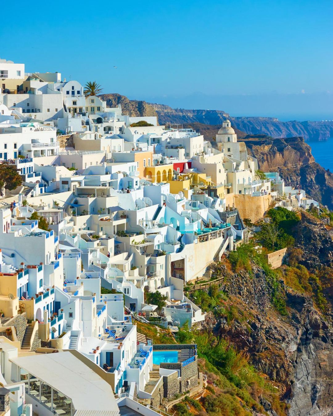 Whitewashed villages cascading down the Santorini caldera cliffs